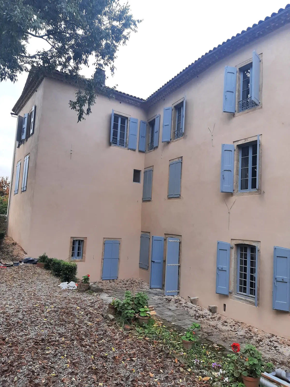 Façade de maison de maître près de Millau après un enduit à la chaux, angle rentrant et portes cintrées