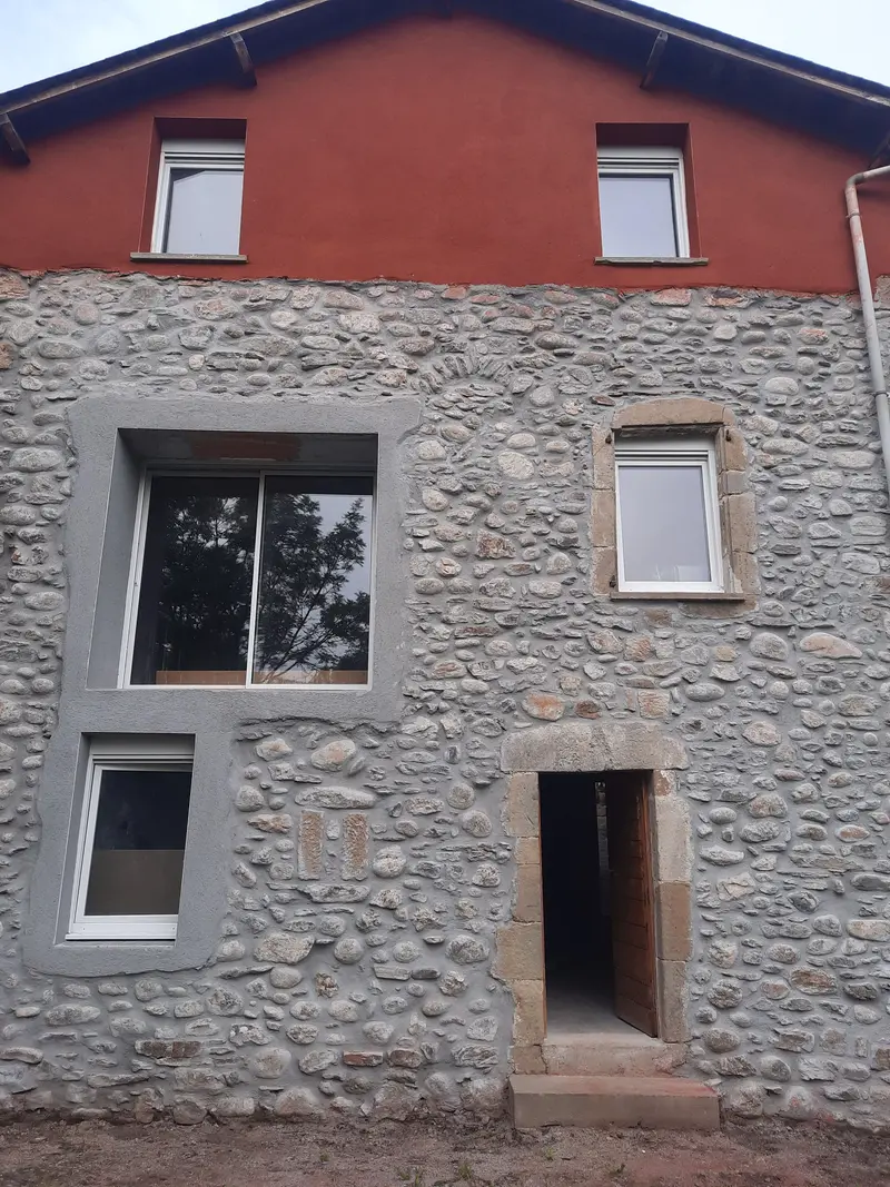 Façade de maison en pierre à moellons ronds à Millau après travaux, joints refaits à la chaux et encadrements enduits
