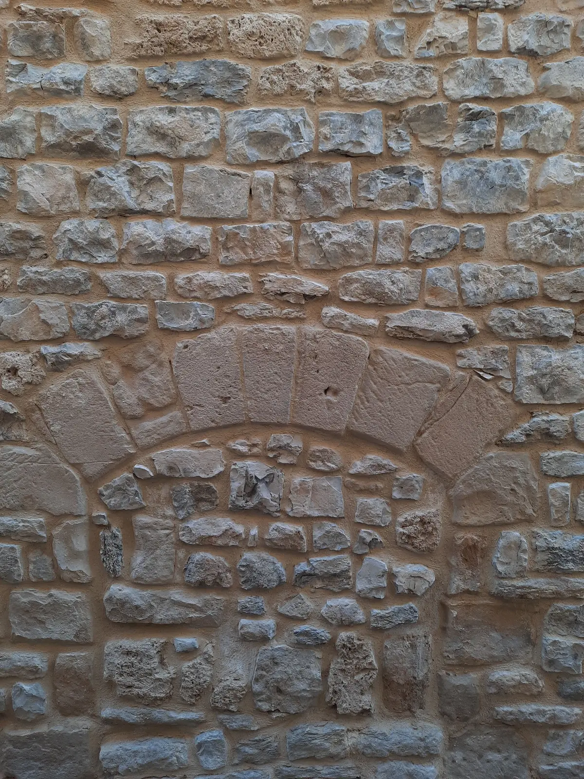Mur en pierre avec arc à clé et ouverture murée à Millau, joints refaits à la chaux