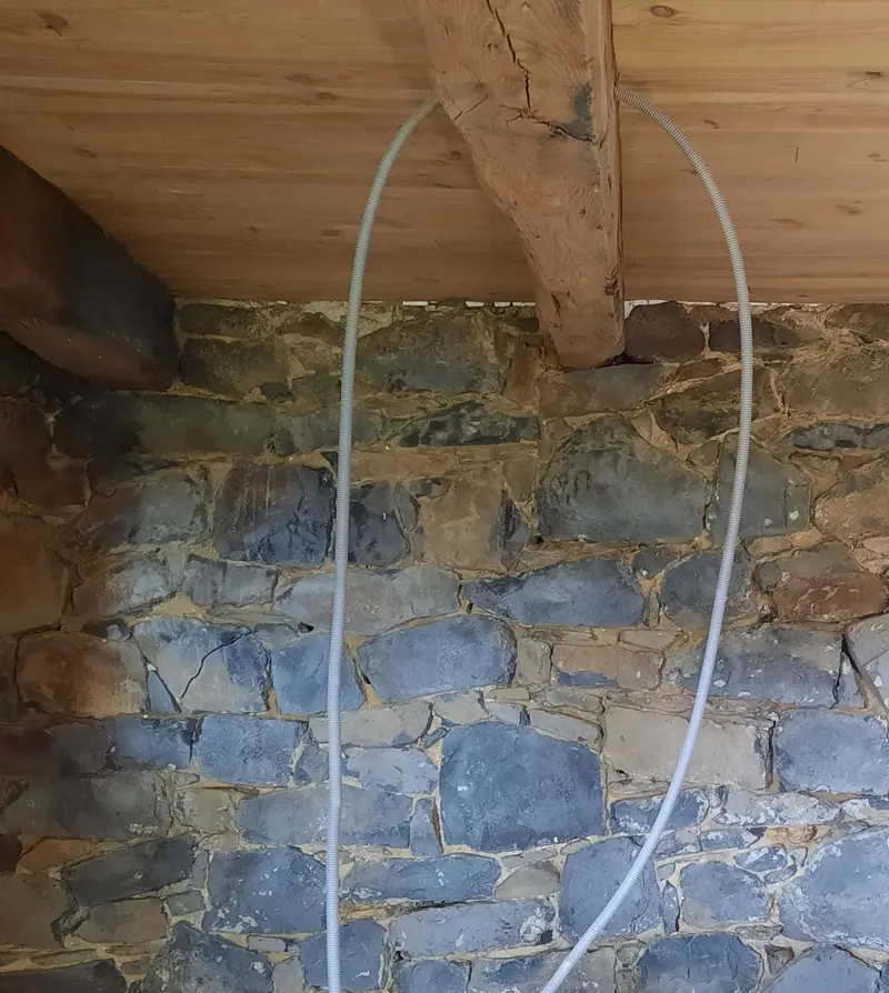 Mur intérieur en pierre apparente sous poutres à Millau, avant la réfection des joints